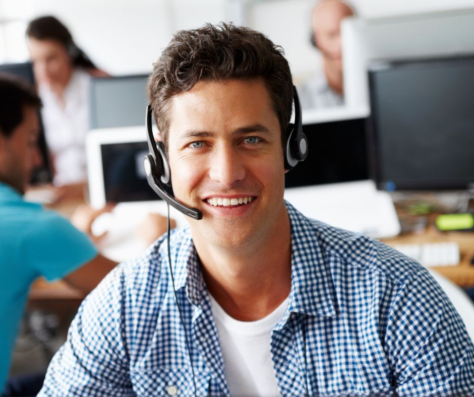Young man with a computer headset smiling.